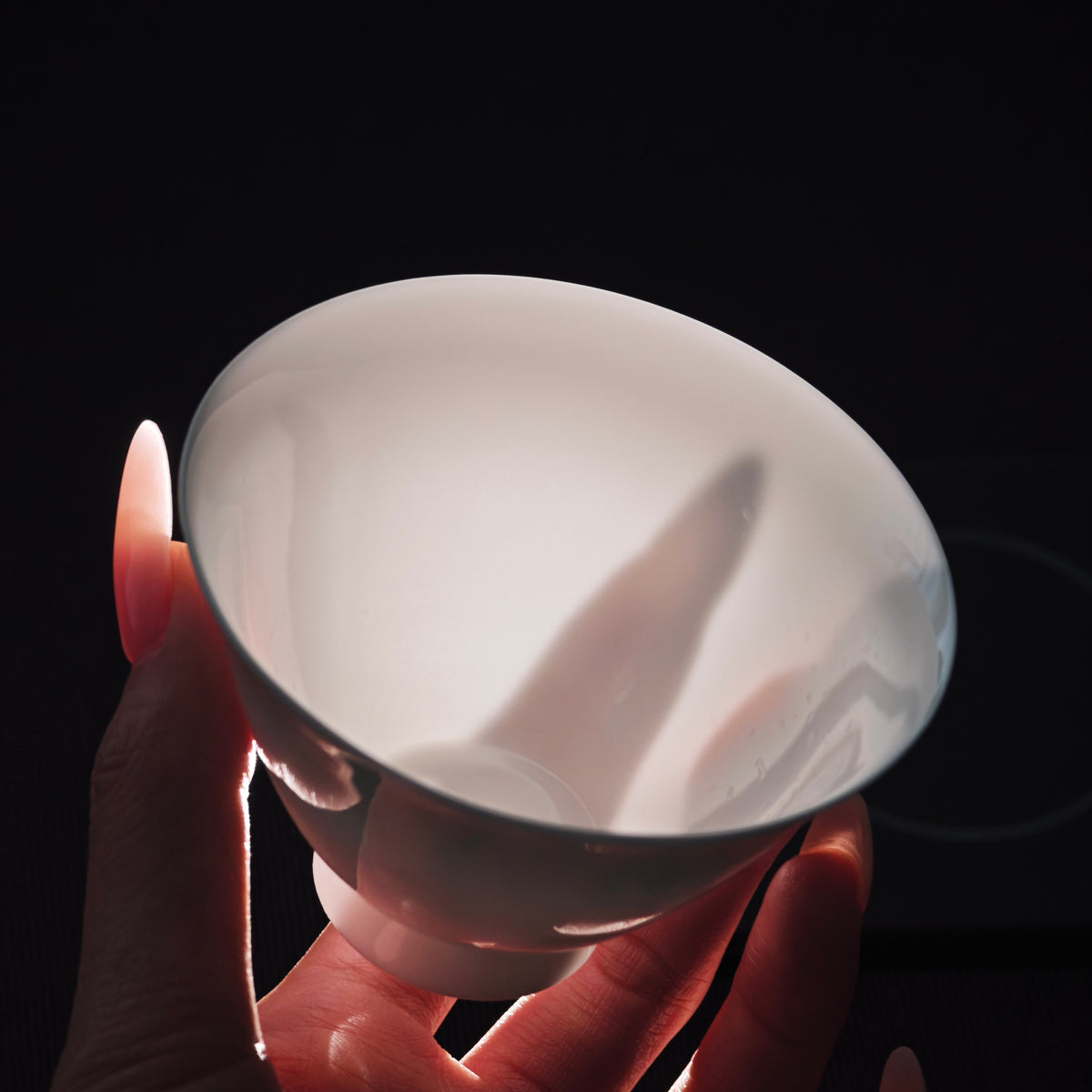 White gaiwan held toward the light