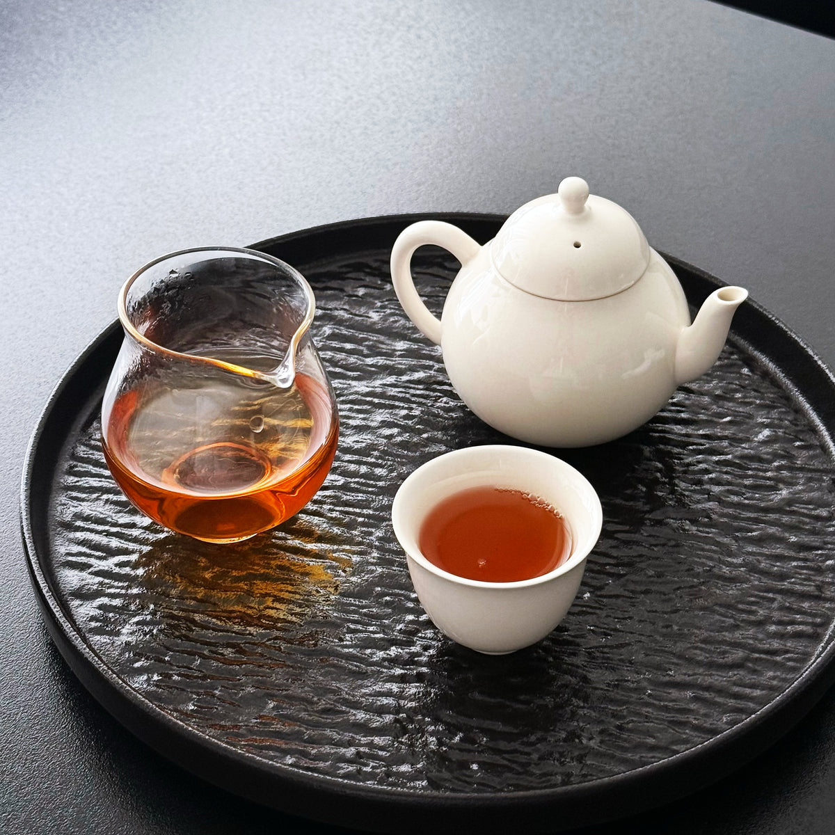 Teapot and cup with a glass pitcher on a textured tray