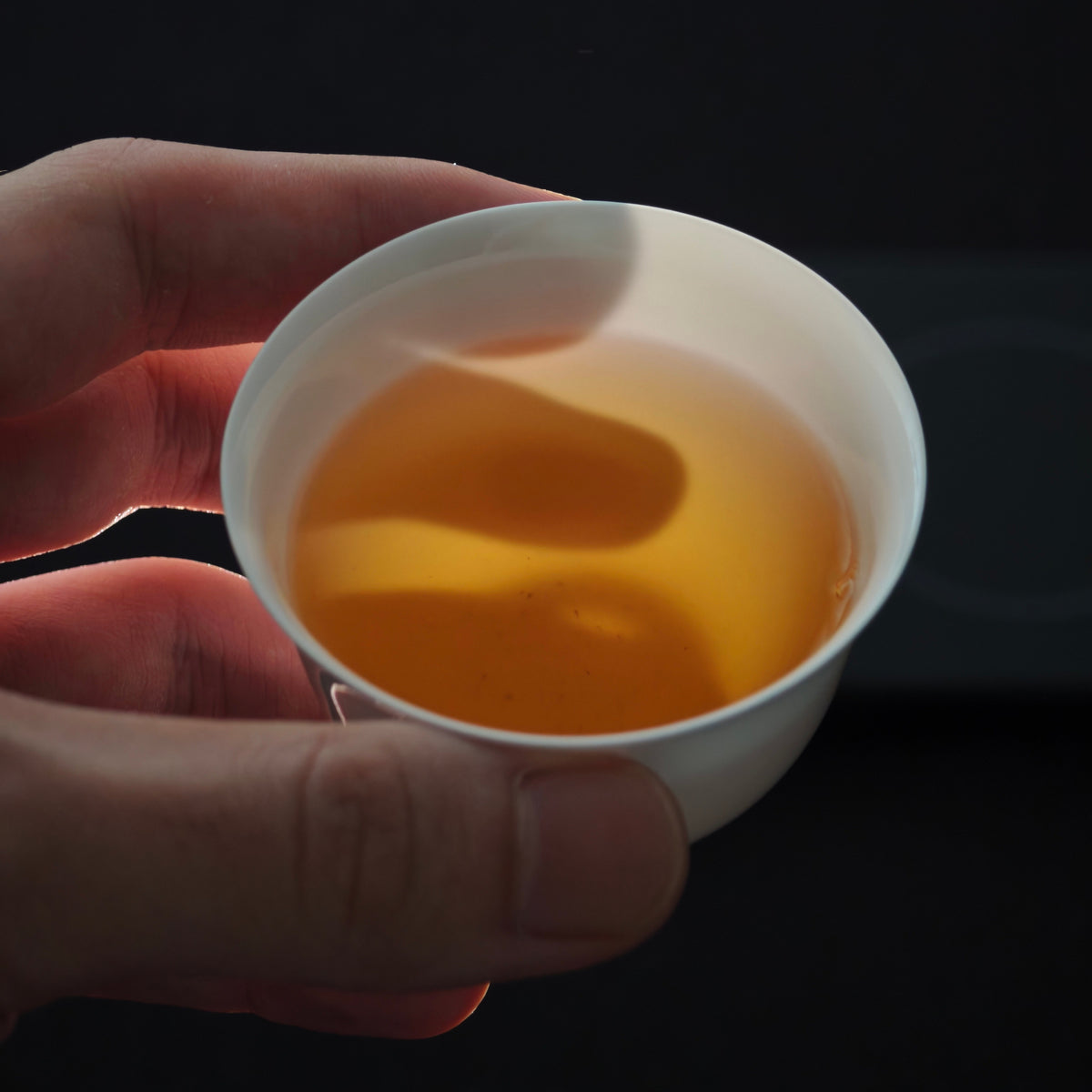 White teacup held with amber tea inside