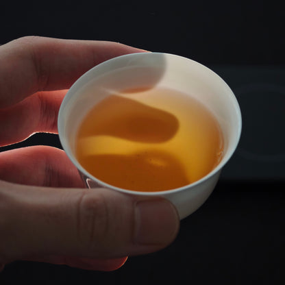 White teacup held with amber tea inside