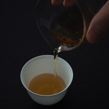 Tea being poured into a white tasting cup